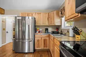 Una cocina con armarios de madera, un refrigerador de acero inoxidable, un microondas y una estufa.