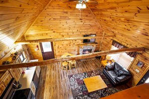 A wooden cabin interior with a dining area, kitchen, and living room.
