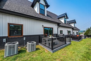 A modern house with a white exterior, black roof, and a covered outdoor patio area with a black railing.