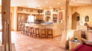 A spacious kitchen with a central island, wooden bar stools, and a cozy seating area with a red couch. - Martinique (Lake Havasu City)