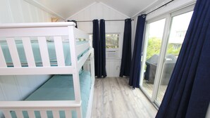 Une chambre avec des lits superposés, une porte-fenêtre coulissante et une vue sur l’extérieur.