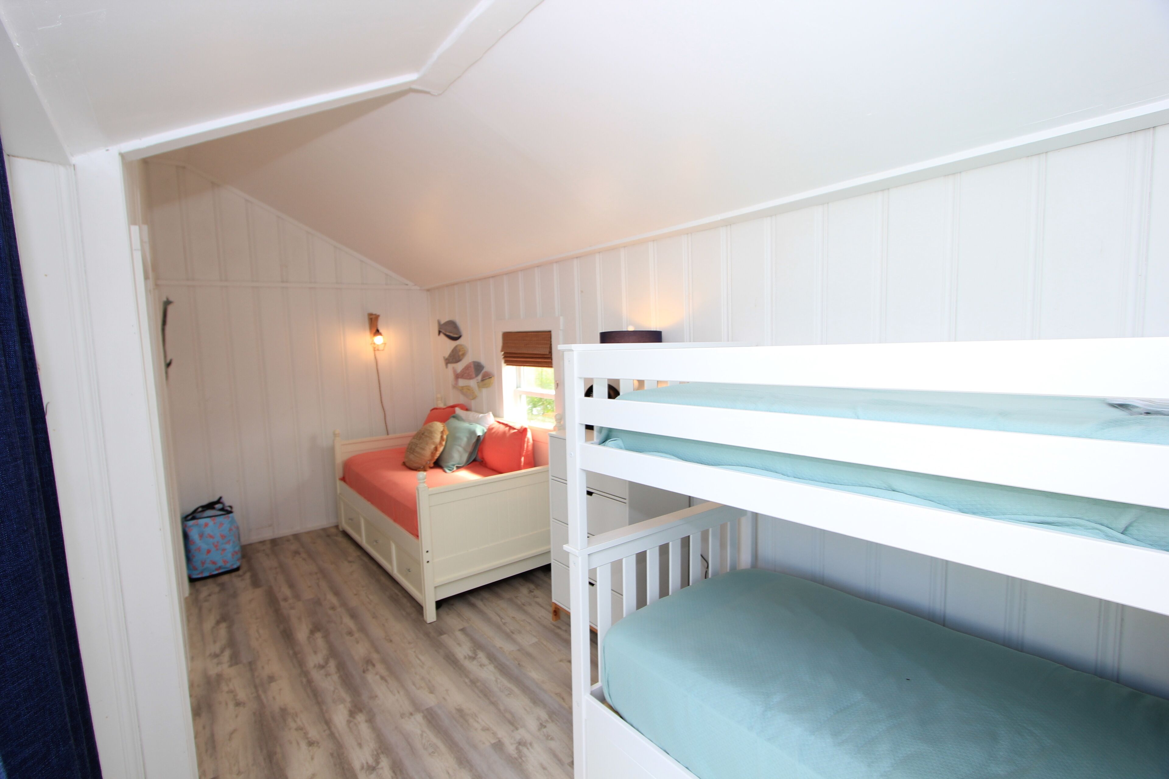 A child's bedroom with a bunk bed, a single bed, and a small desk.