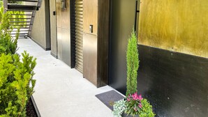 A modern building exterior with a metal staircase, a door, and a small garden area with plants. - modern, luxury, private entrance, garden, terrace, and stunning mountain views. (Brixen)
