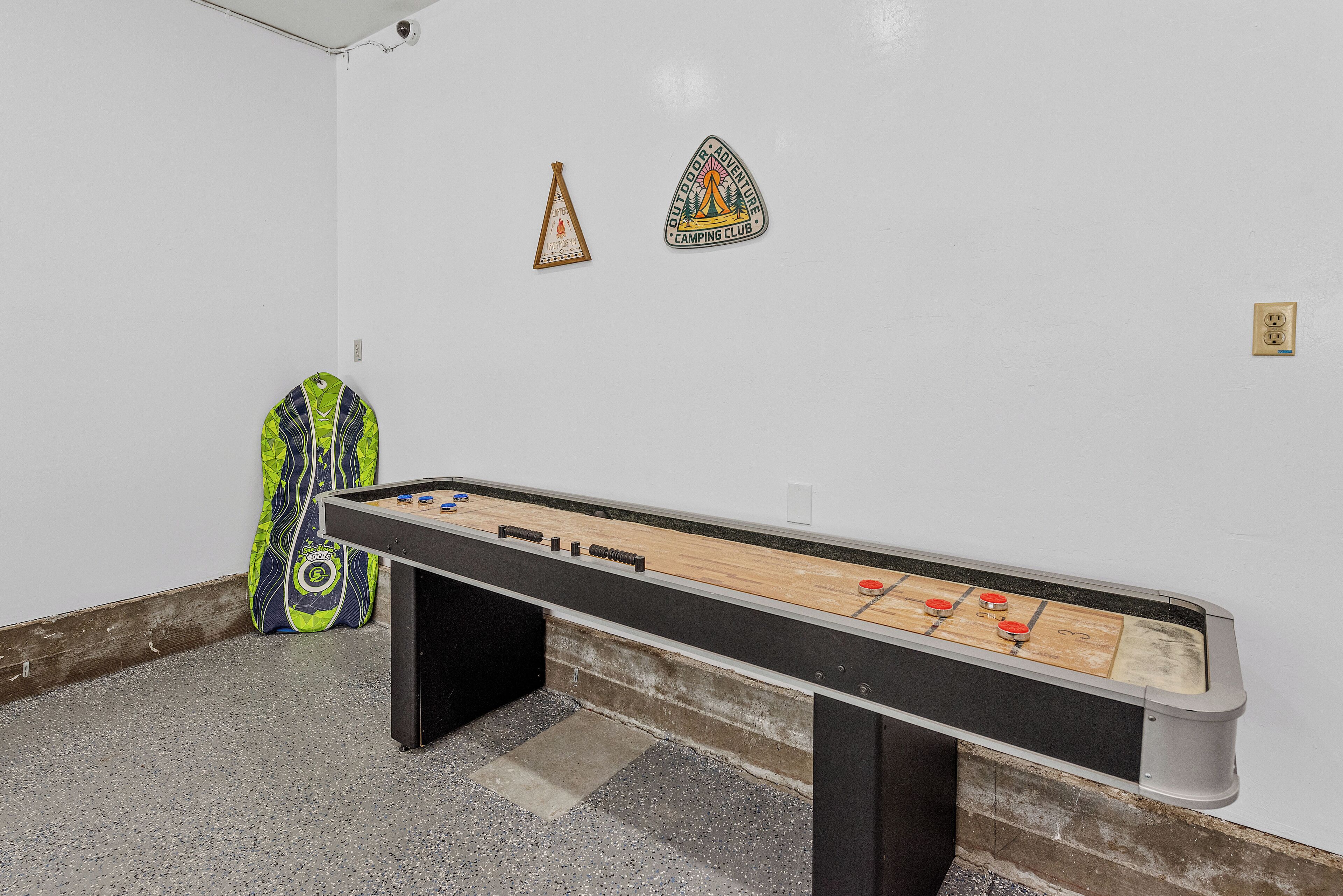 A foosball table in a room with a white wall, a small triangular decoration, and a green bag.