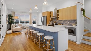 Una cocina moderna con una isla central, armarios de madera y una barra con taburetes.