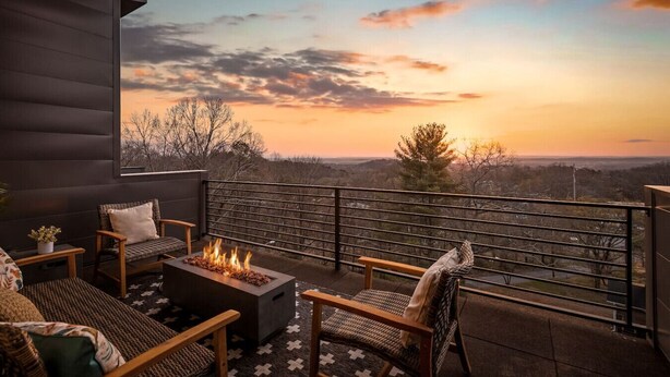 Un balcón con una chimenea, asientos y vistas al atardecer.