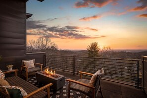 Un balcón con una chimenea, asientos y vistas al atardecer.
