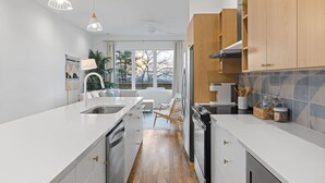 Una cocina moderna con encimeras blancas, armarios de madera y una isla central.