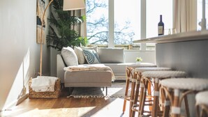 Una sala de estar acogedora con sofá, sillones, una lámpara de pie y un amplio ventanal con vistas.