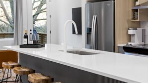 Een moderne keuken met een groot eiland, barkrukken en hanglampen.