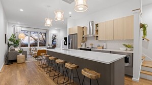 Een moderne keuken met een groot kookeiland, barstoelen en hanglampen.