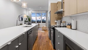 Een moderne keuken met een centraal eiland, houten kastjes en hanglampen.