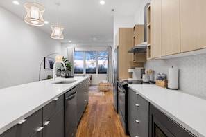A modern kitchen with a central island, wooden cabinets, and pendant lighting. - Nomad - An Atomic Ridge Home (Chattanooga)