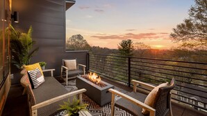 Een balkon met een vuurkorf, zitplaatsen en uitzicht op de ondergaande zon.