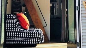 Un espace de vie compact comprenant un canapé, un ventilateur de plafond et un escalier menant à un niveau supérieur.