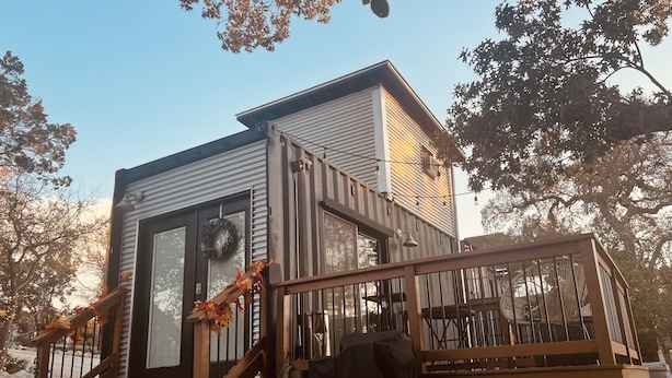 Une maison moderne à deux étages, dotée d’une terrasse et d’un espace salon extérieur abrité.