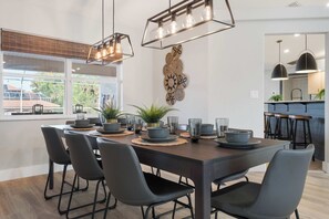 Un comedor moderno con una mesa de madera, sillas negras e iluminación colgante.