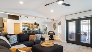 A modern living room with a sectional sofa, a coffee table, and a dining area in the background.