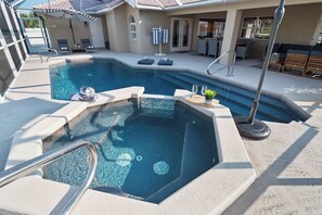 A swimming pool with a hot tub, lounge chairs, and a covered patio area.