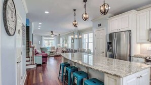 Una cocina amplia con una isla grande, electrodomésticos de acero inoxidable y taburetes de bar color turquesa.