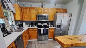 A modern kitchen with wooden cabinets, stainless steel appliances, and a wooden countertop. - What you see is what you get (Arcade)