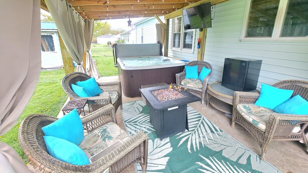 An outdoor patio area with wicker furniture, a hot tub, and a flat-screen TV. - What you see is what you get (Arcade)
