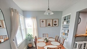 A dining room with a wooden table, chairs, a ceiling fan, and a window with curtains. - What you see is what you get (Arcade)