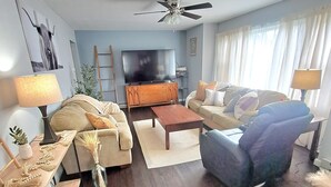 A living room with a sofa, armchair, coffee table, TV, and ceiling fan. - What you see is what you get (Arcade)