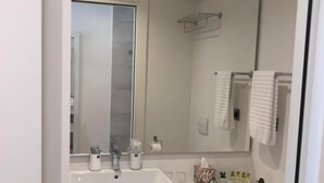 Ein modernes Badezimmer mit einem großen Spiegel, zwei Waschbecken, einer Toilette und ordentlich drapierten Handtüchern.