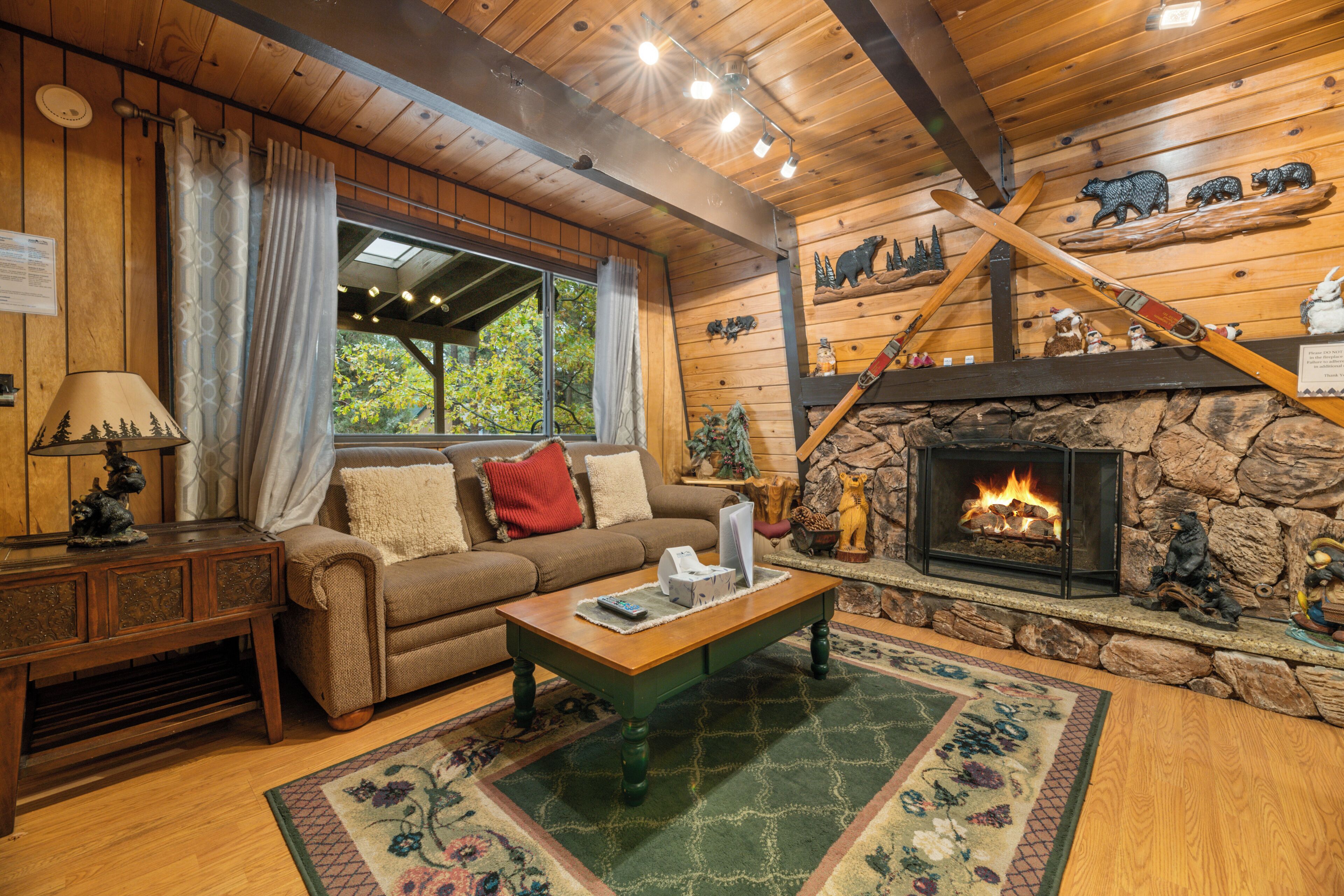 L’intérieur d’un chalet accueillant, avec une cheminée, des murs en bois, un canapé et une table basse.