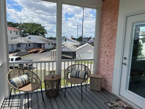 Relax on the covered porch with two wicker chairs and a small table.