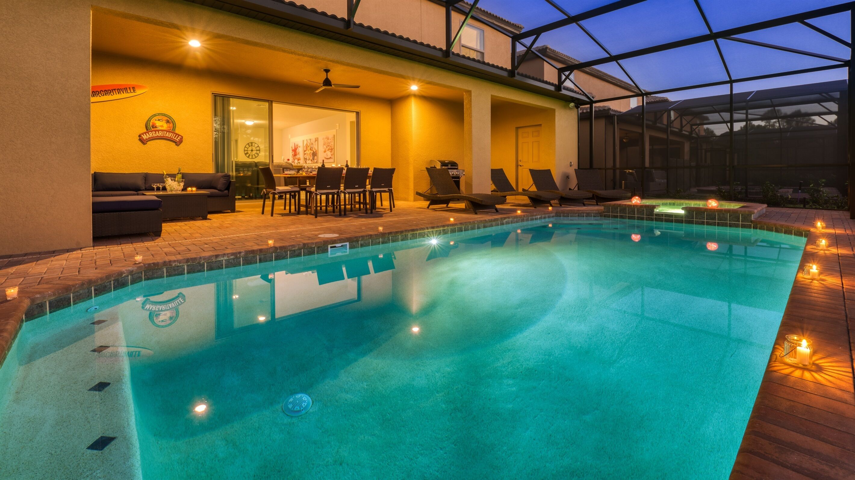 A swimming pool with lounge chairs and a dining area, surrounded by a covered patio.