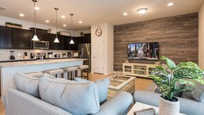 Una sala de estar moderna con un sofá gris, una mesa de centro y un televisor montado en una pared de madera.