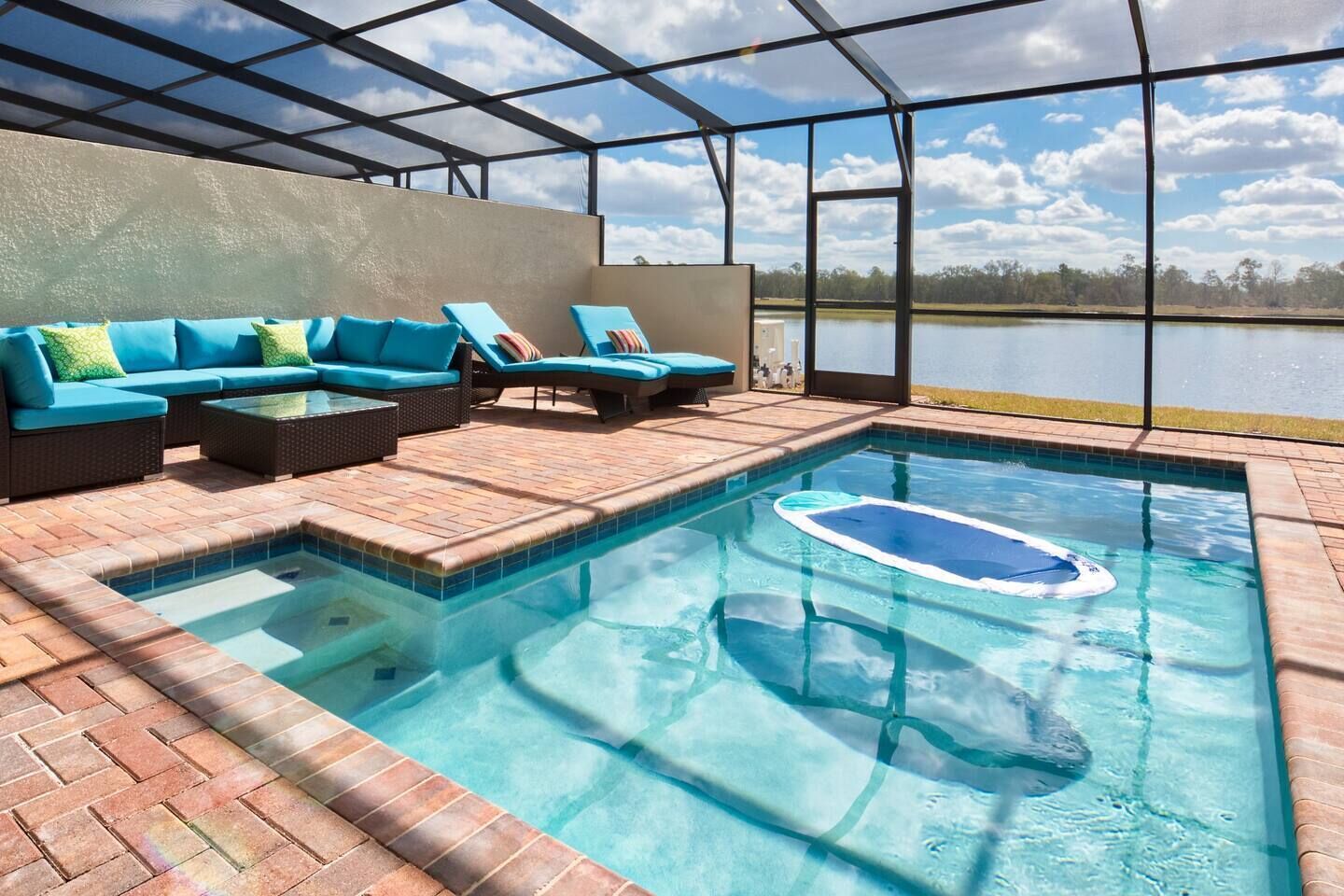 Ein Poolbereich im Innenbereich mit freiem Blick auf den See, ein Sitzbereich mit blauen Kissen und ein Pool mit Whirlpool.