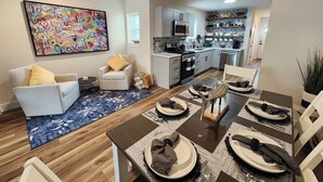 A modern living room with a dining area, a kitchen, and a large colorful artwork on the wall. - Fairview Terrace-Brand New 3BDRM, Central Location  (Atlantic City)