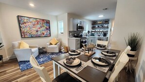 A modern living room with a dining area, a kitchen, and a large colorful artwork on the wall. - Fairview Terrace-Brand New 3BDRM, Central Location  (Atlantic City)