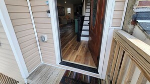 A wooden door leading to a staircase and a living room with a sofa and coffee table. - Fairview Terrace-Brand New 3BDRM, Central Location  (Atlantic City)