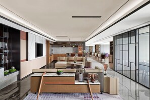 Un espace de vie spacieux et moderne, comprenant un grand canapé, une table basse et un téléviseur. Il y a également une cuisine équipée d’un évier et de placards, ainsi qu’un coin repas avec des chaises et une table.