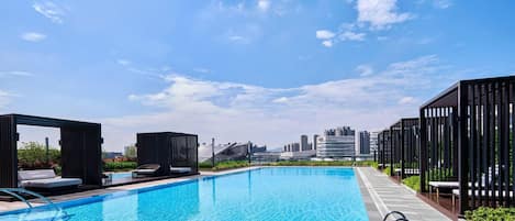 A rooftop swimming pool with a city skyline in the background.