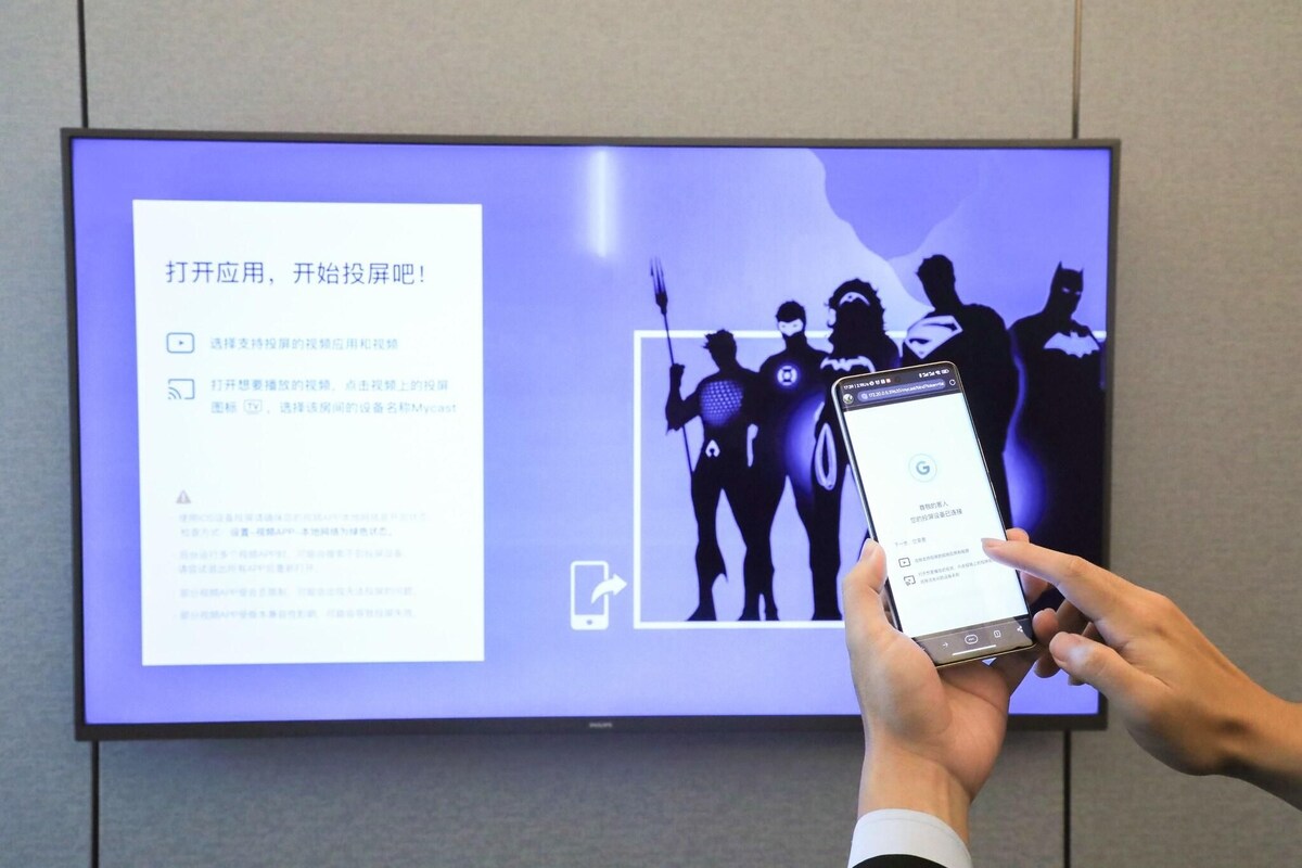 Une personne utilise un smartphone doté de l’interface de recherche Google. L’écran affiche du texte et, en arrière-plan, on peut apercevoir la silhouette de super-héros.