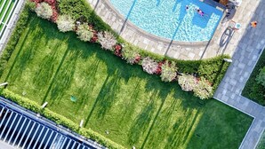 Vue aérienne d’un espace paysager comprenant une piscine, une pelouse parfaitement entretenue et un chemin pavé.