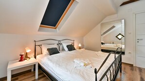A bedroom with a skylight, a bed with white linens, a bedside table with a lamp, and a large mirror on the wall. - Nice home in Vinogradi Ludbreski with sauna (Vinogradi Ludbreski)