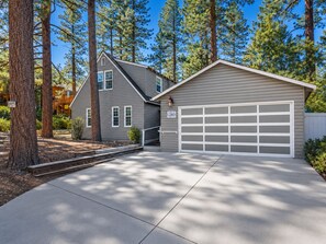 A residential property with a two-car garage, a covered driveway, and a well-maintained lawn. - Country Bear Inn (Big Bear City)