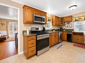 A kitchen with wooden cabinets, stainless steel appliances, a microwave, stove, and dishwasher. - Country Bear Inn (Big Bear City)