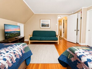 Una habitación con sofá, televisión y cama con colcha.