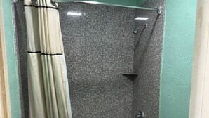 A bathroom with a bathtub, shower, and toilet. - Roadside Inn (Floresville)
