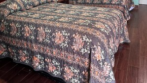 A room with two beds, green walls, and a wooden floor. - Roadside Inn (Floresville)