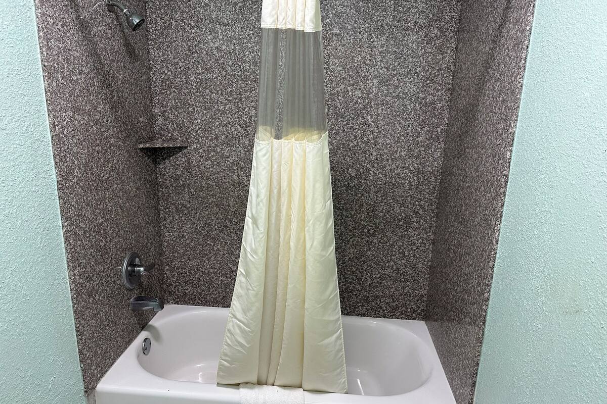 A bathroom with a granite wall, a white sink, and a shower curtain.