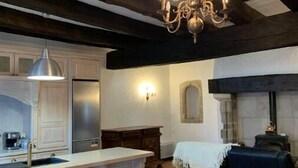 A kitchen with a central island, bar stools, a chandelier, and a fireplace. - Historic Maison du Roy/Upper Chambers 3BR/2 BR Apartment with Balcony & View (Saint-Antonin-Noble-Val)