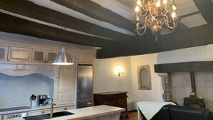 A kitchen with a large island, a chandelier, and a fireplace. - Historic Maison du Roy/Upper Chambers 3BR/2 BR Apartment with Balcony & View (Saint-Antonin-Noble-Val)